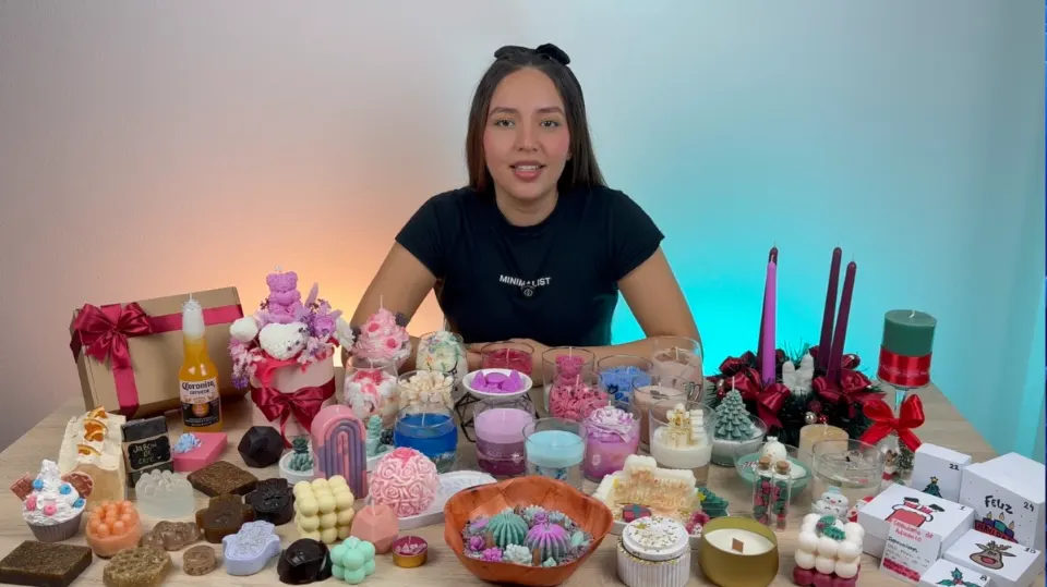 La profesora del curso junto a una mesa llena de velas y jabones artesanales